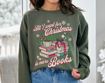 May include: Green sweatshirt with a Christmas-themed design featuring a stack of books, a cup of hot cocoa, and candy canes. The text reads "All I want for Christmas is more Books".