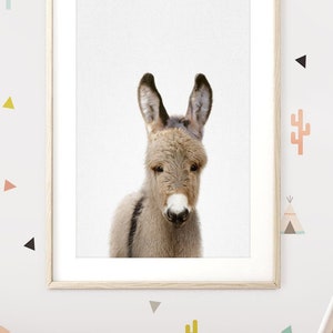 May include: A white teepee tent with a brown and white blanket inside. The teepee is in a room with a white sofa and a framed print of a donkey. The wall is decorated with colourful geometric stickers.