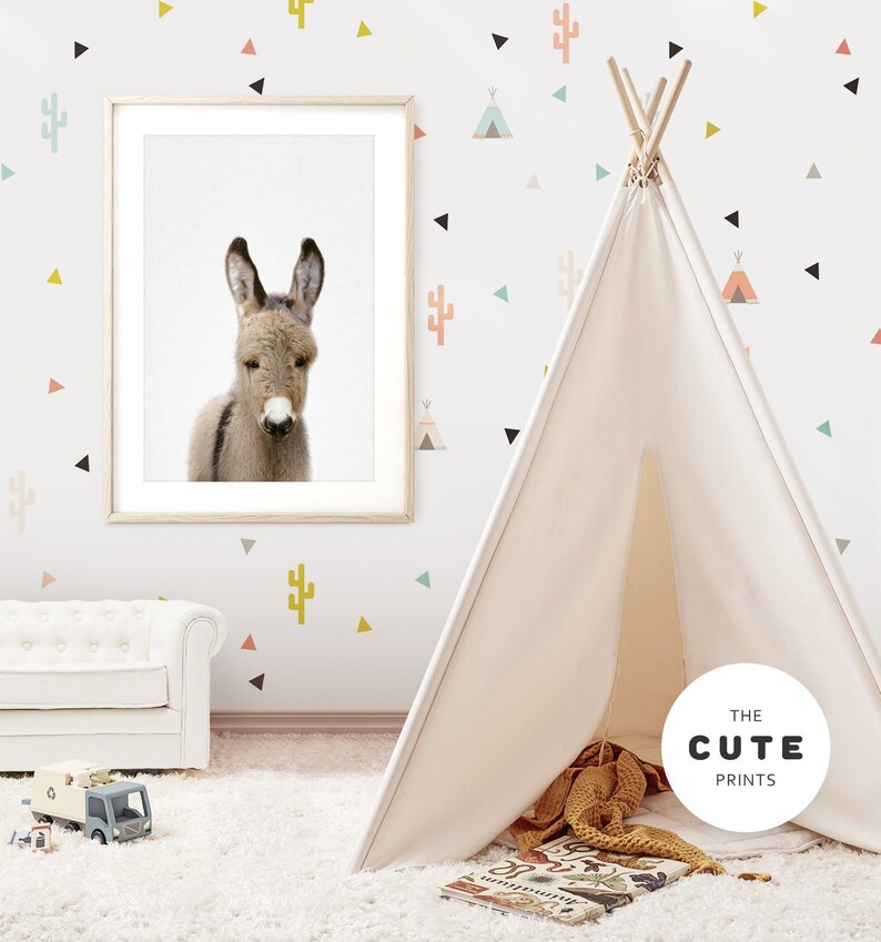 May include: A white teepee tent with a brown and white blanket inside. The teepee is in a room with a white sofa and a framed print of a donkey. The wall is decorated with colourful geometric stickers.