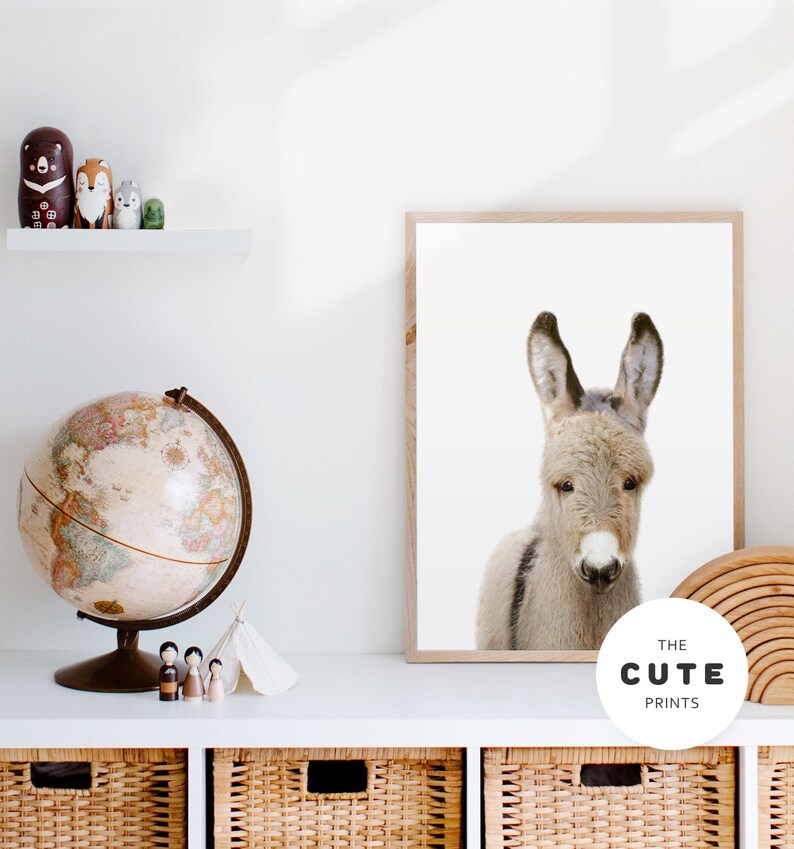 May include: A framed print of a cute donkey with a white background. The print has a brown frame and a white logo with the text "THE CUTE PRINTS" in black.