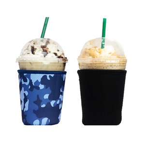 May include: Two iced coffee drinks in clear plastic cups with lids and straws. The coffee on the left has a blue and white camouflage sleeve. The coffee on the right has a black sleeve.