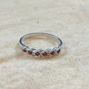 May include: A silver ring with a braided band and small brown gemstones.
