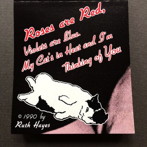 Può includere: Un'illustrazione in bianco e nero di un gatto sdraiato sulla schiena con le zampe in aria. Il testo "Roses are Red, Violets are Blue. My Cat's in Heat and I'm Thinking of You" è scritto in rosso e bianco su sfondo nero. Il testo "© 1990 by Ruth Hayes" è scritto in bianco su sfondo nero.
