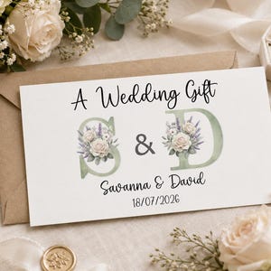 May include: A rectangular white card featuring the text A Wedding Gift, the initials S and D decorated with watercolour floral illustrations of white roses and lavender, the names Savanna and David, and the date 18/07/2026 in black font.