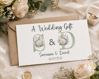 May include: A rectangular white card featuring the text A Wedding Gift, the initials S and D decorated with watercolor floral illustrations of white roses and lavender, the names Savanna and David, and the date 18/07/2026 in black font.