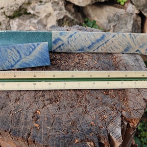 May include: Two pieces of fabric, one blue and white with a pattern and one green, are laid out on a wooden surface next to a ruler. The ruler is 30.5 cm long and has markings in inches and centimetres.