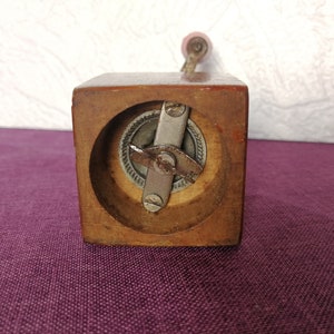 May include: A wooden pepper grinder with a metal grinding mechanism. The grinder has a crank handle and a square base.
