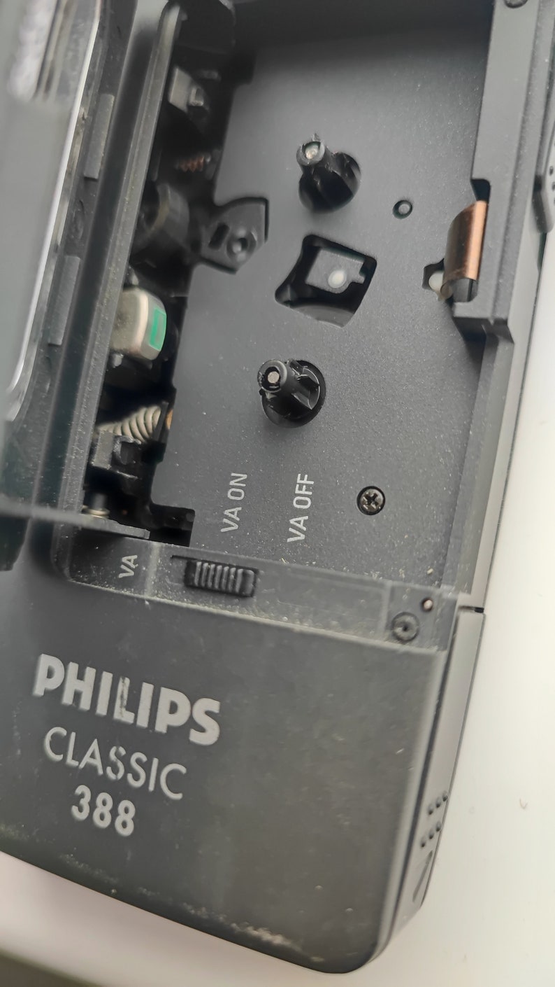 May include: Close-up of a black cassette player with the text "PHILIPS CLASSIC 388" on the front. The player has a cassette tape slot and a volume knob. The text "VA ON" and "VA OFF" are visible on the side of the player.