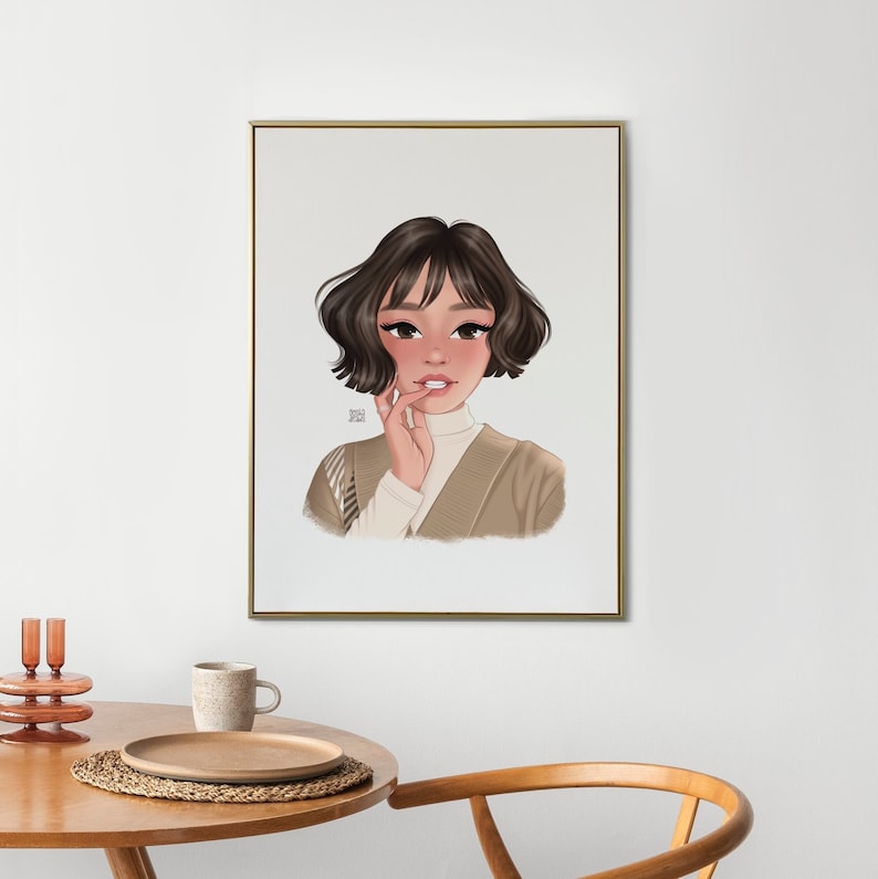 Op de afbeelding: Een ingelijste illustratie van een vrouw met kort bruin haar, die een beige trui draagt en naar de kijker kijkt. De achtergrond is wit.