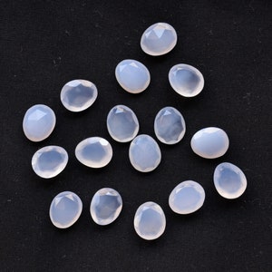 Puede incluir: Una colecci&oacute;n de gemas facetadas de color azul p&aacute;lido, de forma ovalada o de l&aacute;grima. Las gemas est&aacute;n dispersas sobre un fondo negro, mostrando cada piedra un corte &uacute;nico y sutiles variaciones de color y claridad. Ideales para la creaci&oacute;n de joyas.