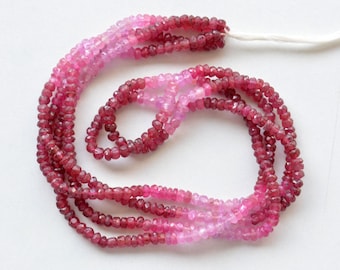 May include: Strands of faceted beads in shades of pink and red, creating a gradient effect. The beads are strung together, forming multiple rows. The beads are small and appear to be gemstones, suitable for jewelry making.