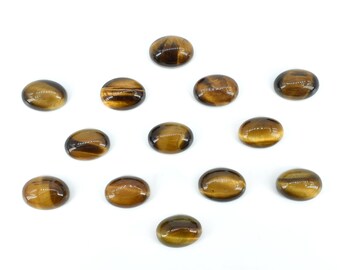 Könnte beinhalten: Ovale Tigerauge-Edelsteine. Die Steine weisen eine Mischung aus Braun- und Goldtönen mit einem Chatoyanz-Effekt auf. Die Edelsteine sind auf weißem Hintergrund angeordnet. Geeignet für die Schmuckherstellung.