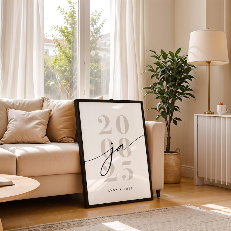 May include: A rectangular framed wall art piece featuring a white background with large, light gray numbers 20, 08, and 25 stacked vertically. The cursive letters ja are centered over the numbers, with the text ANNA &hearts; NOEL printed at the bottom.