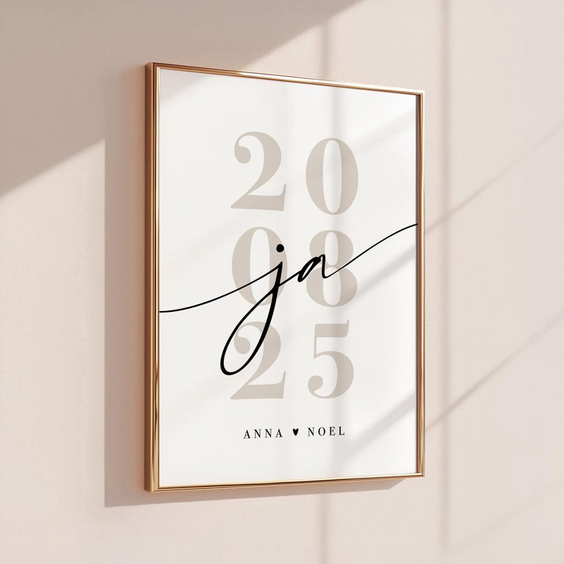 May include: A framed wall art print featuring the large, light gray numbers 2025 stacked vertically. Overlaid in the center is the black cursive text ja. At the bottom, the text ANNA &hearts; NOEL is printed in a simple, clean, black sans-serif font.