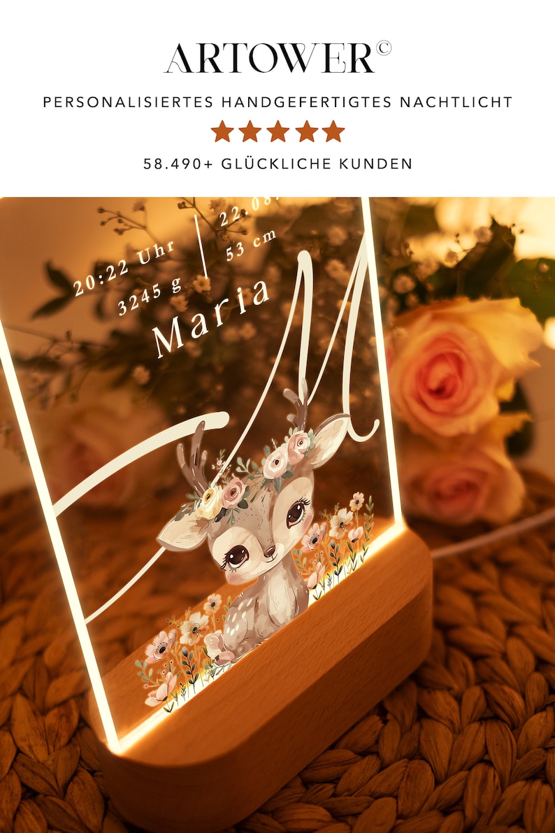 May include: A personalized night light with a deer illustration and floral accents. The light features a clear acrylic panel with the name "Maria", the time "20:22", and the weight "3245 g" and height "53 cm". The light has a wooden base.