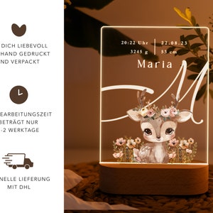 May include: A white acrylic night light with a deer illustration and the text "Maria" and "20:22 Uhr 22.08.23 3245 g 53 cm". The night light has a wooden base.