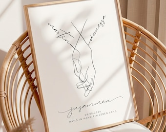 May include: A framed art print featuring a minimalist line drawing of two hands intertwined. The names "Martin" and "Vanessa" are written above the hands, with the word "zusammen" and the date "08.08.2026" below. The phrase "Hand in Hand ein Leben lang" is also included.