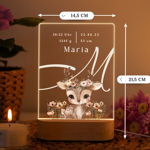 May include: A personalized acrylic night light with a deer illustration and floral accents. The light features the name "Maria" and birth details: 20:22 Uhr, 22.08.23, 3245 g, 53 cm. The light is 14.5 inches tall and 8.5 inches wide.