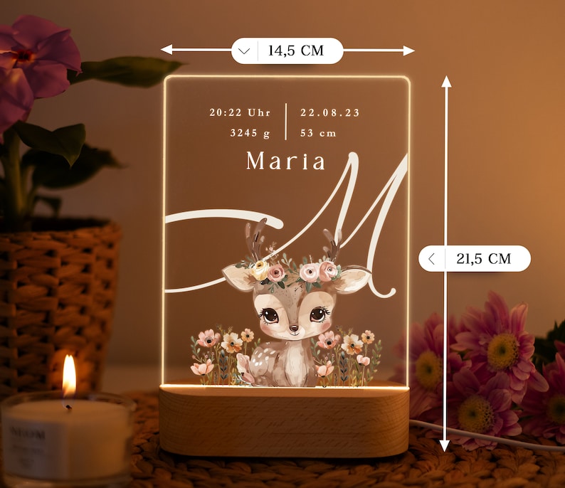 May include: A personalized acrylic night light with a deer illustration and floral accents. The light features the name "Maria" and birth details: 20:22 Uhr, 22.08.23, 3245 g, 53 cm. The light is 14.5 inches tall and 8.5 inches wide.