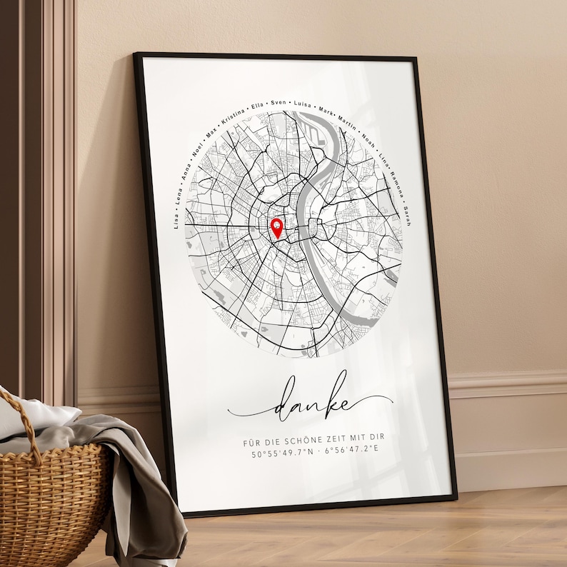 Puede incluir: Impresi&oacute;n enmarcada de un mapa en blanco y negro con un marcador rojo. El mapa es de una ciudad, con nombres en c&iacute;rculo en la parte superior. La palabra "danke" est&aacute; escrita en cursiva debajo, con coordenadas.