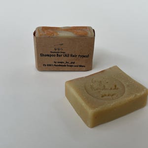 May include: A brown cardboard box with a white shampoo bar inside. The box has the text "GIGI's Handmade Soaps" and "Shampoo Bar (All Hair types)".
