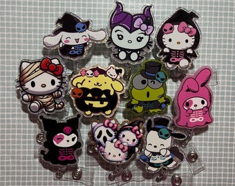 May include: A collection of Halloween-themed character badge reels. The designs include Hello Kitty, My Melody, and other characters dressed as mummies, skeletons, and vampires. Each badge reel has a glittery border and a clear plastic backing.