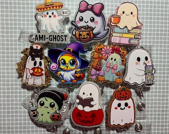 May include: A collection of Halloween-themed badge reels featuring various ghost characters. The designs include ghosts in costumes, holding pumpkins, and with other festive elements. The text "CAMI-GHOST" is visible on one of the reels.