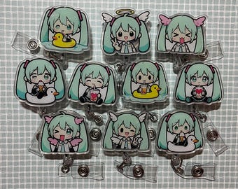 May include: A collection of nine acrylic badge reels featuring a chibi-style character with long teal hair. Each reel displays a different pose, including the character with a yellow rubber duck, drinking bubble tea, or wearing small pink wings.