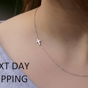 May include: A delicate silver chain necklace with a small silver cross pendant.