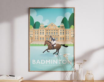 May include: A vertical poster featuring a stylized illustration of a horse and rider crossing a water jump in front of a large tan building. The text BADMINTON GLOUCESTERSHIRE is printed at the bottom against a light blue background with green hills.
