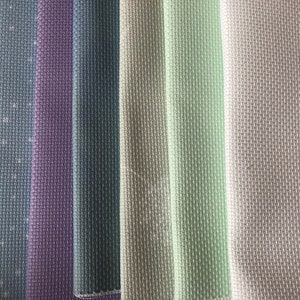 May include: A close-up of seven fabric swatches in various shades of blue, purple, green, and gray. The fabric has a textured weave.