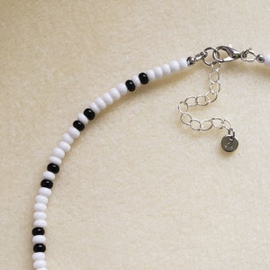 May include: A white and black beaded necklace with a silver clasp.