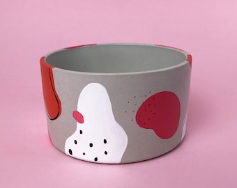 Round concrete pot with hand painted multi-coloured abstract pattern