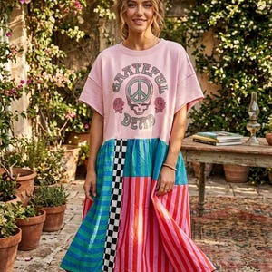 May include: A pink t-shirt dress with the text "Grateful Dead" above a skull and peace sign graphic. The dress features a color-blocked skirt with blue, green, red, and black and white checkered panels. The dress is knee-length.