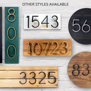 Puede incluir: Una variedad de letreros de n&uacute;meros de casa con diferentes estilos y colores. Los n&uacute;meros est&aacute;n hechos de metal y est&aacute;n unidos a diferentes tipos de madera. Los n&uacute;meros incluyen 5930, 800, 1543, 10723, 3325, 564 y 832.