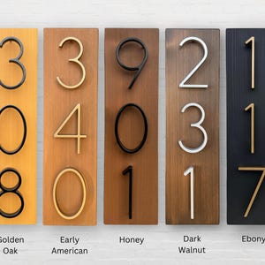 Puede incluir: Cinco letreros de madera con diferentes manchas de madera, cada uno con un conjunto de n&uacute;meros en una fuente moderna. Los letreros est&aacute;n etiquetados con los nombres de las manchas de madera: Golden Oak, Early American, Honey, Dark Walnut y Ebony.