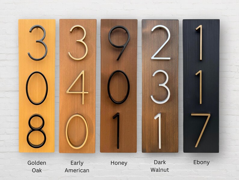 Puede incluir: Cinco letreros de madera con diferentes manchas de madera, cada uno con un conjunto de n&uacute;meros en una fuente moderna. Los letreros est&aacute;n etiquetados con los nombres de las manchas de madera: Golden Oak, Early American, Honey, Dark Walnut y Ebony.