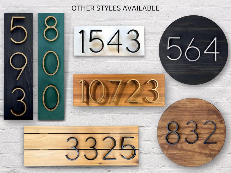 May include: A selection of house number signs in various styles and colours. The numbers are made from metal and are mounted on different types of wood. The numbers include 5930, 800, 1543, 10723, 3325, 564, and 832.