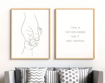 Puede incluir: Dos impresiones artísticas enmarcadas con marcos de madera. Una presenta un dibujo lineal de una mano adulta sosteniendo la mano de un niño. La otra impresión tiene el texto: "El tiempo no es reembolsable. Úsalo con intención."