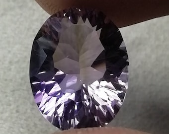 Peut inclure: Une pierre précieuse d'améthyste ovale et facettée. La gemme présente des nuances de violet, du lavande clair au violet foncé, avec une surface brillante et réfléchissante. Les facettes créent un jeu d'ombre et de lumière.