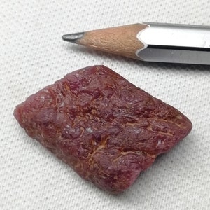 Peut inclure: Une pierre pr&eacute;cieuse de rubis rouge fonc&eacute; brute de forme l&eacute;g&egrave;rement rectangulaire. Le rubis est &agrave; peu pr&egrave;s de la taille d'une gomme &agrave; effacer.