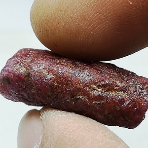 Peut inclure: Gros plan sur une pierre pr&eacute;cieuse de rubis rouge fonc&eacute;. Le rubis est brut et a une finition naturelle non polie.