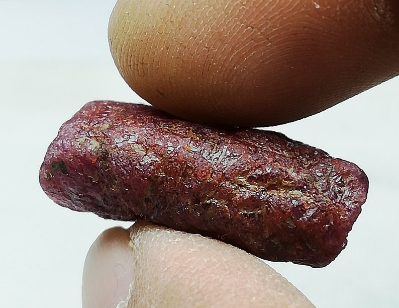 Peut inclure: Gros plan sur une pierre pr&eacute;cieuse de rubis rouge fonc&eacute;. Le rubis est brut et a une finition naturelle non polie.
