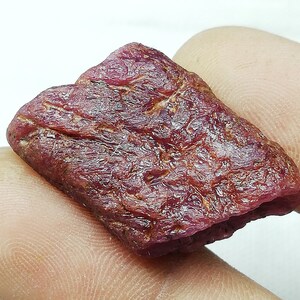 Peut inclure: Une pierre pr&eacute;cieuse de rubis rouge brute avec une couleur profonde et riche. Le rubis a une finition naturelle non polie et est un bel exemple de cette pierre pr&eacute;cieuse.