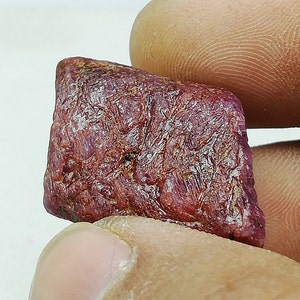 Peut inclure: Une pierre pr&eacute;cieuse de rubis rouge brute avec une couleur profonde et riche. La pierre pr&eacute;cieuse a une finition naturelle non polie et est un bel exemple de rubis brut.