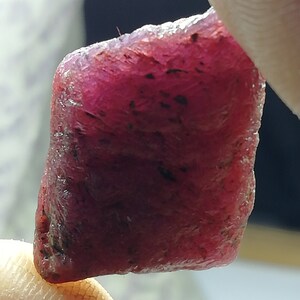 Peut inclure: Une pierre pr&eacute;cieuse de rubis rouge fonc&eacute; brute de forme l&eacute;g&egrave;rement rectangulaire.