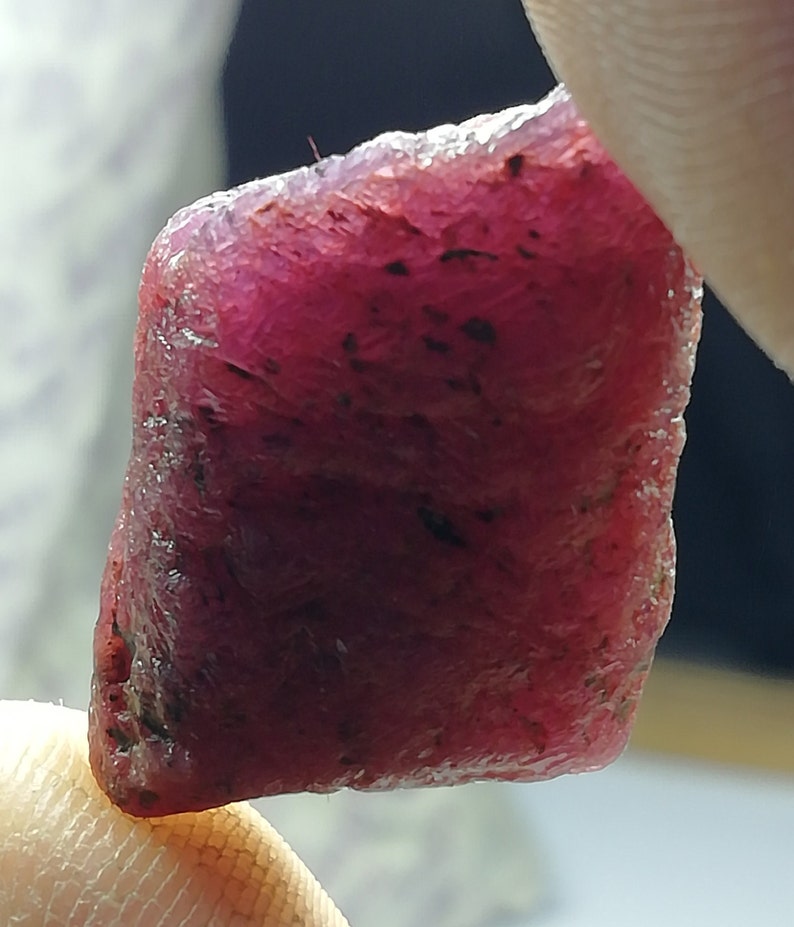 Peut inclure: Une pierre pr&eacute;cieuse de rubis rouge fonc&eacute; brute de forme l&eacute;g&egrave;rement rectangulaire.
