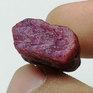 Peut inclure: Gros plan sur une pierre pr&eacute;cieuse de rubis brute non polie. Le rubis est de couleur rose fonc&eacute; et a une texture brute et naturelle.