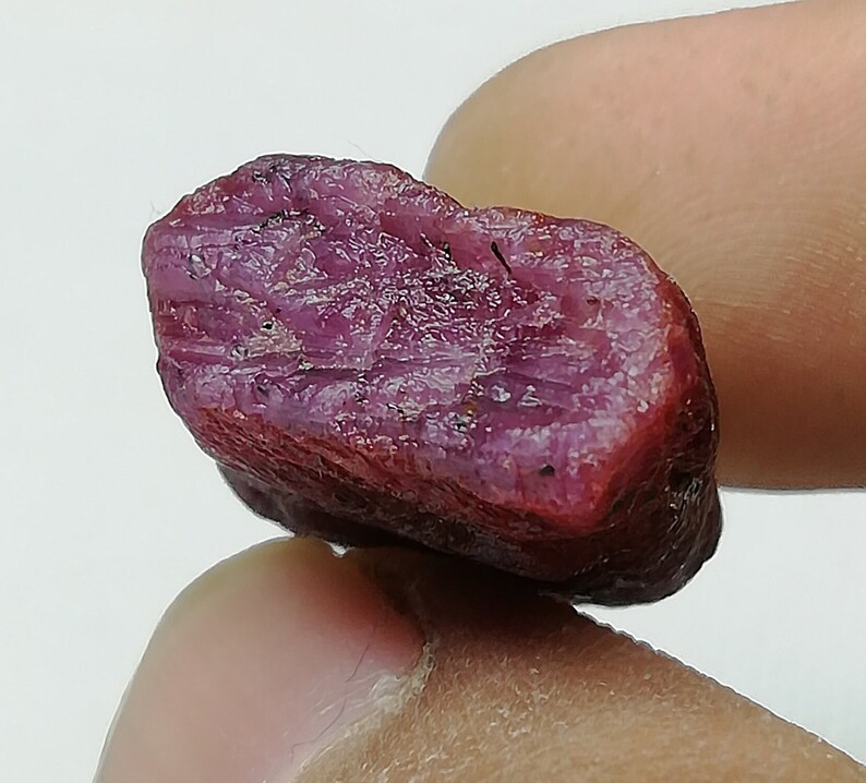 Peut inclure: Gros plan sur une pierre pr&eacute;cieuse de rubis brute non polie. Le rubis est de couleur rose fonc&eacute; et a une texture brute et naturelle.