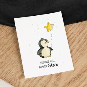 Op de afbeelding: Een aquarel-illustratie van een pinguïn die een gele sterballon vasthoudt. De tekst "Leuchte hell kleiner Stern" staat onder de pinguïn.